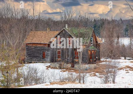 Ein altes, verlassene, gruselig aussehendes Bauernhaus im Winter auf einem Bauernhof im ländlichen Kanada Stockfoto