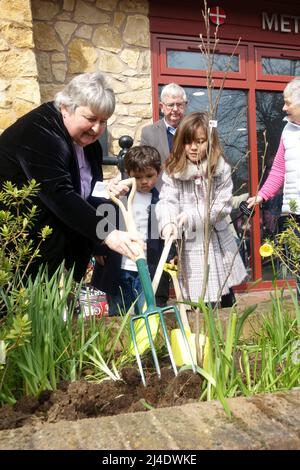 Kirchenminister und zwei Kinder Pflanzen einen Baum zur Feier der Queens Platinum Jubillee 2022 Stratford upon Avon UK Stockfoto