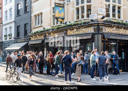 Kunden, die vor dem Pub Dog and Duck an der Ecke Bateman Street und Frith Street in Londons Soho trinken, wenn das Wetter in Großbritannien wärmer wird Stockfoto