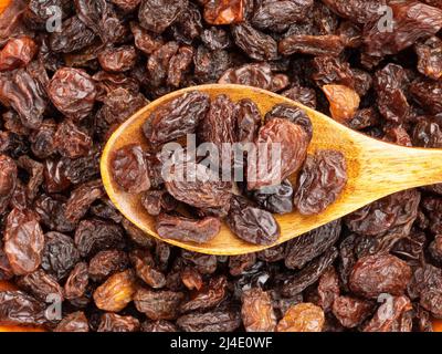 Rosinen in Holzlöffel isoliert auf Hintergrund von Rosinen. Makro. Vegetarisches Konzept Stockfoto