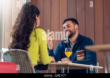 Junges Touristenpaar, das sich unterhielt und in einem Hotel frühstückte Stockfoto