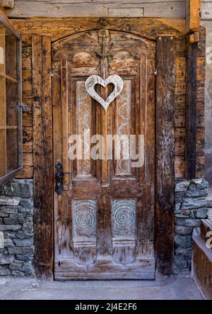Eine rustikale Holztür mit hängender herzförmiger Dekoration Stockfoto