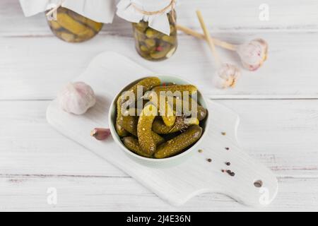 Eingelegte Gurken, Gewürze und Knoblauch auf weißem Holztisch konservieren Stockfoto