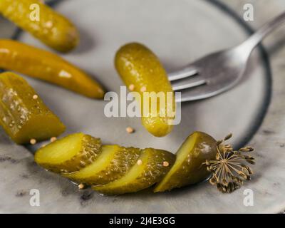 Eingelegte Gurken, Gewürze und Knoblauch auf einem grauen Teller konservieren Stockfoto