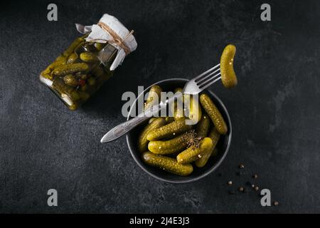 Eingelegte Gurken, Gewürze und Knoblauch auf dunklem Tisch konservieren Stockfoto