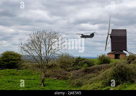 Ein Hubschrauber der Royal Air Force CH-47 Chinook fliegt an einem Frühlingstag mit niedrigen grauen Wolken tief und dicht an der Windmühle in Brill, Buckinghamshire, Großbritannien, vorbei. Stockfoto