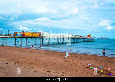 Blick auf den Paignton Beach - Ein langer Pier ragt von diesem beliebten Sandstrand zum Schwimmen und in der Nähe Cafés und Arkaden. Stockfoto