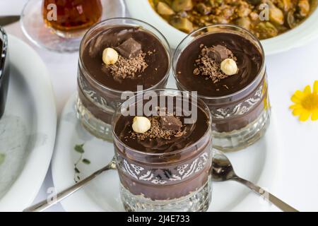 Dessert mit Kakaopudding, geschichtet mit Keksen in Staylish-Gläsern auf dem Ramadan-Tisch.garniert mit Nuss und Schokolade. Stockfoto