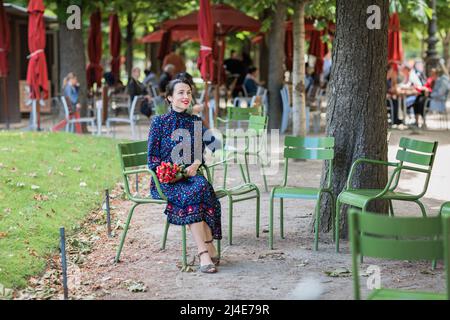 Attraktive Frau in einem blauen Kleid sitzt im Park Stockfoto