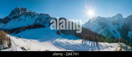 Im Winter scheint die Sonne über der schneebedeckten Bergkette Stockfoto