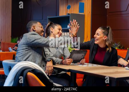 Eine Gruppe von multirassischen Geschäftsleuten lächelt und gibt einander hohe fünf Stockfoto