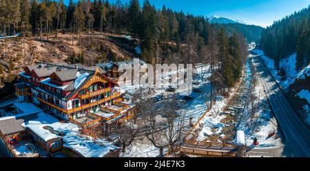 Blick auf schönes Hotel umgeben von Bäumen auf schneebedeckten Landschaft im Dorf Stockfoto
