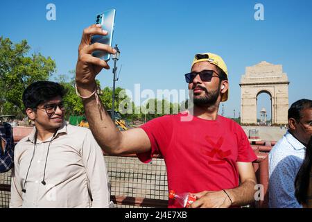 Touristen machen Selfies mit ihren Smartphones vor dem India Gate. Das Kriegsdenkmal befindet sich auf dem Rajpath, am östlichen Rand der „zeremoniellen Achse“ von Neu Delhi, früher Kingsway genannt Stockfoto