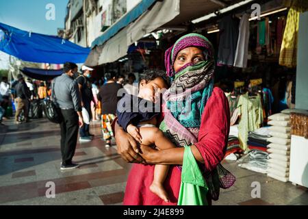 Die alte indische Bettlerin mit Baby bittet auf der Straße von Neu Delhi, Indien, um Almosen Stockfoto