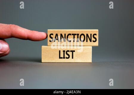 Symbol der Sanktionsliste. Holzblöcke mit Konzeptwörtern Sanktionsliste auf schönem grauen Hintergrund. Geschäftsmann Hand. Geschäftliche politische Sanktionen li Stockfoto