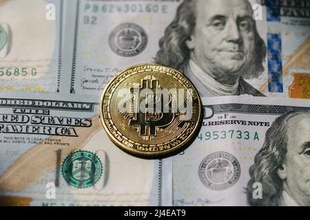 Goldene, glänzende Bitcoin-Krypto-Währungsmünzen auf hundert US-Dollar-Scheinen. Unterschied zwischen Kryptowährungen und Bargeld Stockfoto