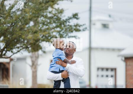Ein kleiner Junge im Vorschulalter wird von seinem Vater festgehalten und sie reden Stockfoto