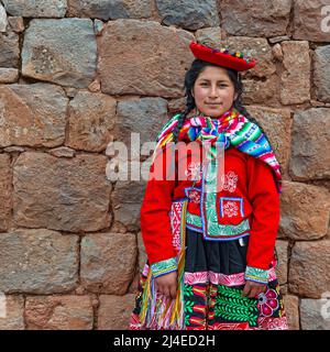 Porträt einer jungen, peruanischen indigenen Quechua-Frau mit traditioneller Textilkleidung vor der Inka-Mauer in Cusco, dem Heiligen Tal der Inka, Peru. Stockfoto