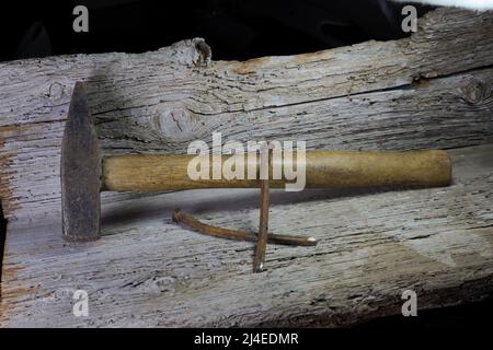 Hammer und alte geschmiedete Nägel liegen auf einem alten Holzregal Stockfoto