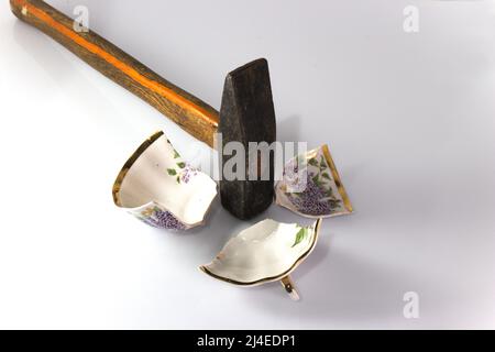 Becher durch einen Hammer gebrochen. Im Holzhintergrund. Konzept. Stockfoto