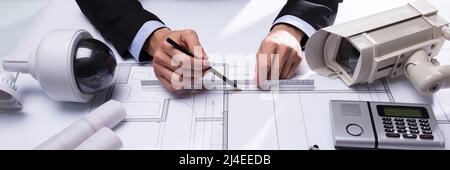 Nahaufnahme der Architekt Hand Zeichnung Blaupause mit Ausrüstungsgegenstände für die Gefahrenabwehr auf dem Schreibtisch Stockfoto