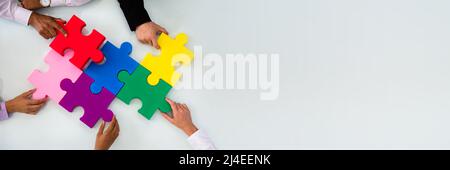 Gruppe von Geschäftsleuten farbenfrohe Lösung Puzzle auf dem Schreibtisch im Büro Stockfoto