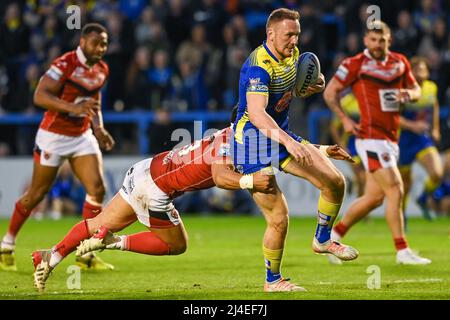 Ben Currie #11 von Warrington Wolvesis in Angriff genommen von Elijah Taylor (13) von Salford Red Devils Stockfoto