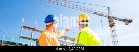 Ansicht der Rückseite zwei männlichen Architekten tragen, hardhat an der Baustelle auf der Suche Stockfoto