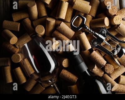 Festliche Komposition. Eine Flasche Rotwein, ein Weinglas und ein Korkenzieher auf dem Hintergrund von Weinkorken. Viele Objekte. Weinprobe, som Stockfoto