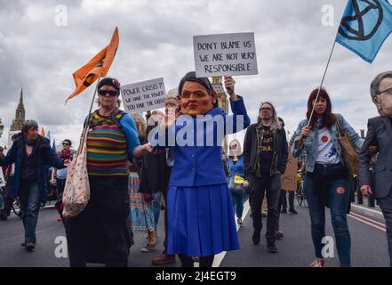 London, Großbritannien, 13.. April 2022. Ein Protestler mit einer Priti Patel Maske auf der Westminster Bridge. Extinction Rebellion Demonstranten marschierten durch das Zentrum Londons und forderten, dass die Regierung gegen die ökologische und Klimakrise handelt. Stockfoto