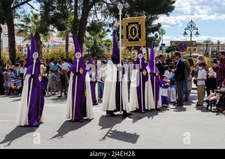 Sevilla, Spanien; 14. April 2022: Büßer der Bruderschaft der 'Las Cigarreras' in einer Prozession während der Karwoche. Stockfoto