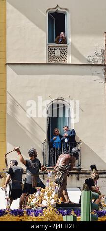 Sevilla, Spanien; 14. April 2022: Menschen beobachten während der Karwoche eine Prozession von ihren Balkonen aus. Bruderschaft der „Las Cigarreras“ Stockfoto