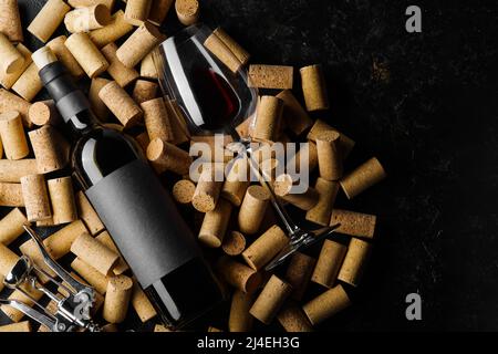 Stilvolles Urlaubsgemisch. Eine Flasche Rotwein und ein Weinglas vor dem Hintergrund von Weinkorken. Weingut, Weinkeller, Weinsammlung, Verkostung Stockfoto