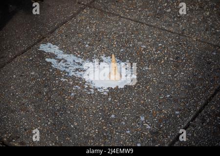 Der abgelassene Eiskegel schmilzt auf dem Bürgersteig Stockfoto
