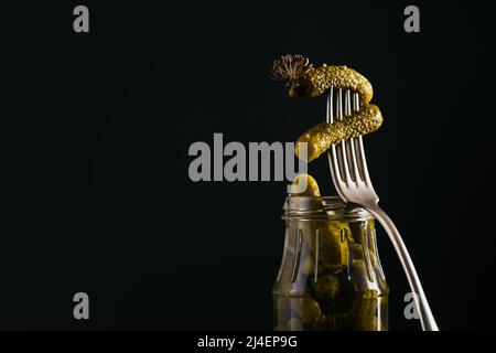 Eingelegte Gurken, Gewürze und Knoblauch auf dunklem Tisch konservieren Stockfoto
