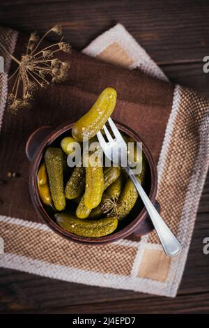 Gurken, eingelegte Gurken auf einer Gabel, Schüssel mit mariniertem Gemüse Stockfoto