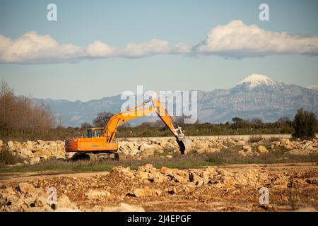 Raupenbagger, der Steinhaufen freiräumt. Orangefarbenes Gerät Stockfoto