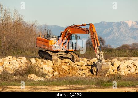 Raupenbagger, der Steinhaufen freiräumt. Orangefarbenes Gerät Stockfoto