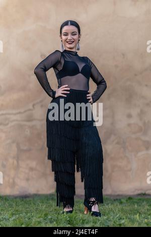 Ganzkörperportrait einer lächelnden Flamenco-Ballerina mit schwarzen Fransenhosen Stockfoto