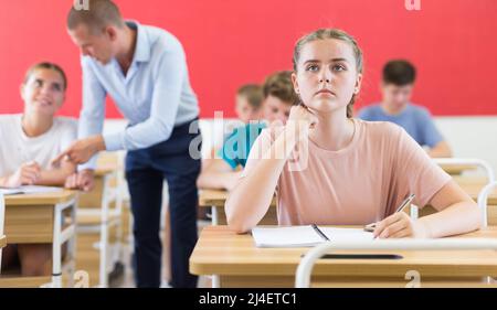 Teenager-Mädchen macht Notizen von Lehrer Vortrag in der Hochschule Stockfoto