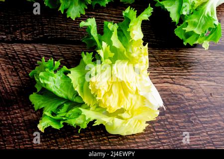 Nahaufnahme Blick auf die frische Escarole: Ein Stück Escarolesalat auf einem Holzhintergrund Stockfoto