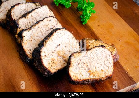 Geröstete Hirtenschwein-Medaillons: Scheiben saftiges Schweinefilet auf einem Holzschneidebrett Stockfoto