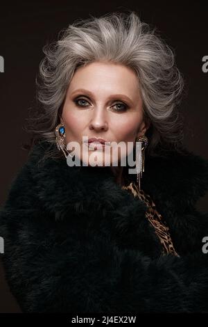 Porträt einer schönen älteren Frau in Leopardenbluse und Pelzmantel mit klassischem Make-up und grauem Haar. Stockfoto