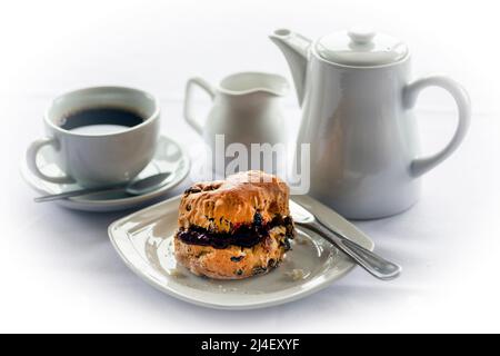 Kaffee, Kaffeetasse, Kaffeekocher und Fruchtkegel mit Himbeermarmelade auf weißem Hintergrund. Stockfoto