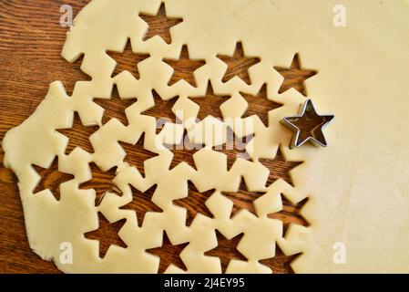 Roher Zucker-Keksteig, der mit einem Stern-Keksschneider auf der Theke ausgerollt wird, für Weihnachten oder andere Feiertage, die zu Hause, Browntown, Wisconsin, USA, gebacken werden Stockfoto