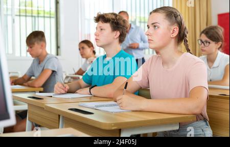 Teenager-Mädchen macht Notizen von Lehrer Vortrag in der Hochschule Stockfoto