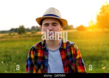 Unschärfe lustige junge Frau geschlossen Augen auf Natur Sonnenuntergang Hintergrund draußen. Nahaufnahme Porträt Mädchen Ausdruck, Emotion. Konzept der Schlaflosigkeit. Depression Stockfoto