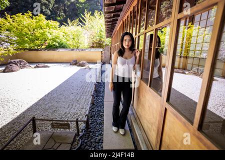 Junge Chinesin, die neben einem japanischen Steingarten steht Stockfoto