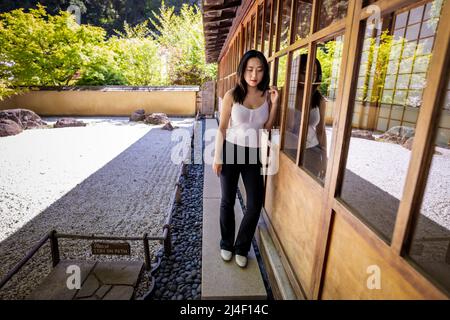 Junge Chinesin, die neben einem japanischen Steingarten steht Stockfoto