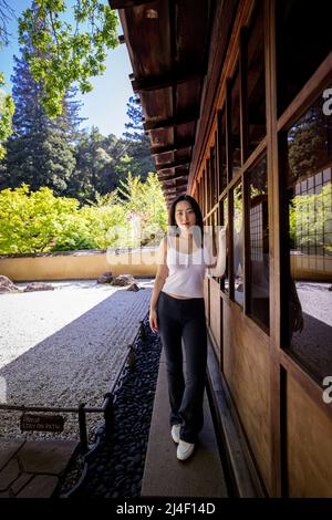 Junge Chinesin, die neben einem japanischen Steingarten steht Stockfoto